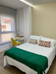 a bedroom with a large bed and a yellow chair at Casa da Fonte in Rianjo