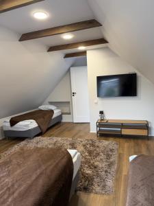 a room with two beds and a flat screen tv at Apartamentai LUKA in Marijampolė