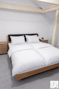 ein großes Bett mit weißen Laken und Kissen in der Unterkunft Lichtloft Fränkische Schweiz in Ebermannstadt