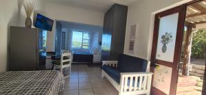 a bedroom with a bed and a chair and a window at To C Garden Cottage in Mossel Bay