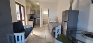 a kitchen with a refrigerator and a living room at To C Garden Cottage in Mossel Bay