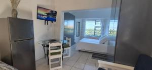 a small room with a bed and a table and a desk at To C Garden Cottage in Mossel Bay