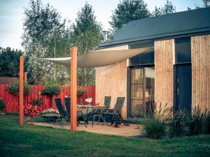 a patio with a table and chairs under an umbrella at Osada Puszczy Śpiew in Grotów