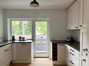 a kitchen with white cabinets and a sliding glass door at Ferienwohnung IMMI in Ruhpolding