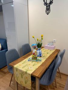 a dining room table with a yellow table cloth and blue chairs at Apartament NIEBO Ustroń in Ustroń