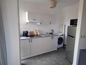 a white kitchen with a sink and a refrigerator at Studio moderne 33m2 Design cosy Wi Fi gratuit in Courcouronnes