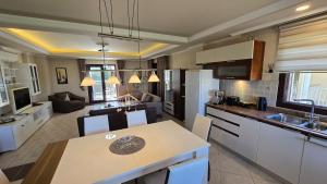 a kitchen and living room with white cabinets and a table at Side Beach Villarında Dubleks Daire in Side