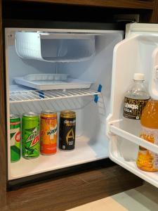 an open refrigerator with cans of soda and drinks at Shanti Regency in Guwahati