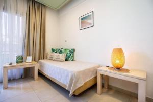 a bedroom with a bed and two tables and a window at Central Thassos luxury Apartment 4u in Limenas