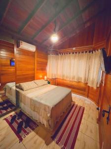 a bedroom with a bed in a room with wooden walls at Pousada Casas Eleganza in Santa Teresa