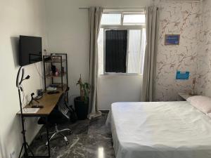 a bedroom with a bed and a desk and a window at Linda Kitnet mobiliada in São Vicente