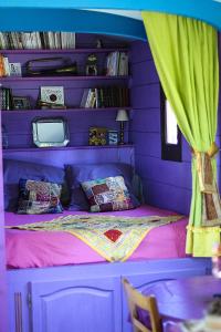 a purple bedroom with a bed with a purple wall at Roulotte de cirque à Rocamadour in Rocamadour