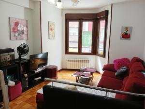 a living room with a red couch and a tv at Gascona con Deli in Oviedo