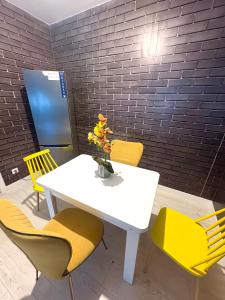 a white table with yellow chairs and a vase with flowers at Residence 2 in Ploieşti