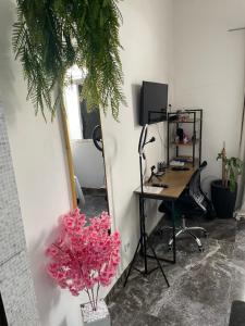 an office with a desk with a computer and pink flowers at Linda Kitnet mobiliada in São Vicente