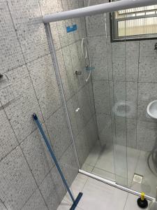 a shower with a glass door and a sink at Linda Kitnet mobiliada in São Vicente +9 photos