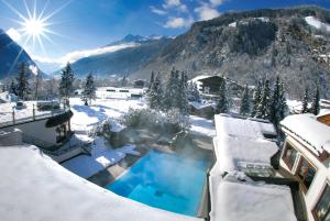 a house covered in snow with a swimming pool at Relais&Châteaux Spa-Hotel Jagdhof in Neustift im Stubaital