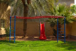 a playground with a red slide and two ladders at Lemon Tree Guest House in Riyadh