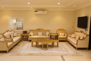 a living room with couches and a flat screen tv at Lemon Tree Guest House in Riyadh