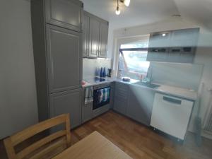a kitchen with gray cabinets and a table and a window at Älgklinten with type 2 charger in Brograngen