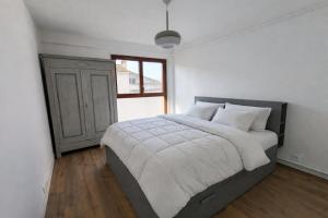 a bedroom with a bed with white sheets and a window at Les toits du Lot in Villeneuve-sur-Lot