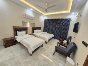 a bedroom with two beds and a chair at Regency Guest House Peshawar in Peshawar