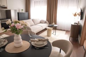 a living room with a table with a vase of flowers at Alma Suites Győr in Győr