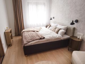 a bedroom with a bed with white sheets and a window at Alma Suites Győr in Győr