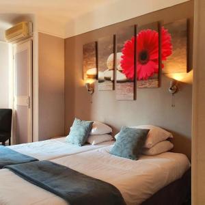 two beds in a hotel room with a red flower on the wall at Le Petit Château - Cannes in Cannes