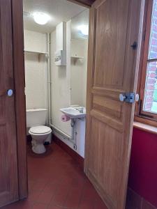 a bathroom with a toilet and a sink and a door at La Loge Appartement 1 in Beauquesne +17 photos