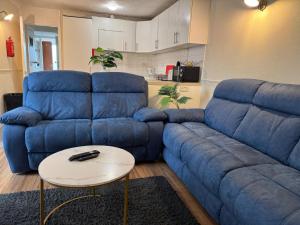 a living room with a blue couch and a table at Amirs house in Hackington
