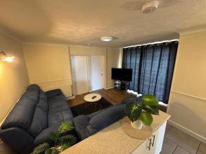 a living room with a blue couch and a television at Amirs house in Hackington