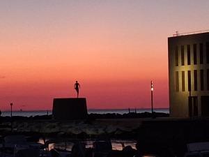 a statue of a person standing on a ledge at sunset at Hotel Touring in Livorno