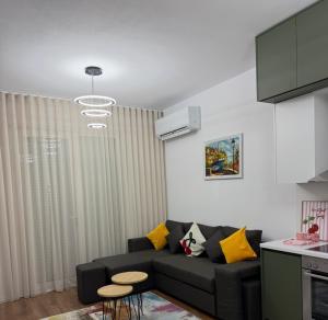 a living room with a black couch and yellow pillows at White Apartment in Kamëz