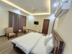a hotel room with a bed and a chair at Regency Guest House Peshawar in Peshawar