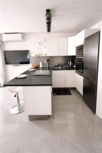 a kitchen with white cabinets and a black refrigerator at Studio cosy, Centre Port, Piscine, proche plage in Cap d'Agde +17 photos