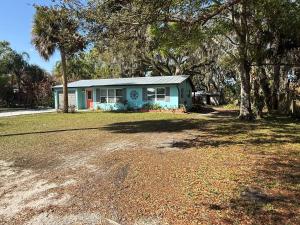 a small blue house on a yard with trees at 1008 Gardens in Vero Beach