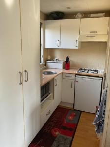 a small kitchen with white cabinets and a sink at Chalet C5 in Heel