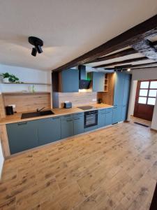 a large kitchen with blue cabinets and a wooden floor at Old City Apartment Möckmühl in Möckmühl +5 photos