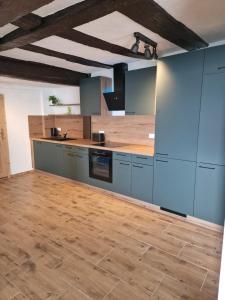 a kitchen with blue cabinets and a wooden floor at Old City Apartment Möckmühl in Möckmühl