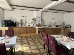 a dining room with two tables and a kitchen at Hotel Eulenhof in Gransdorf