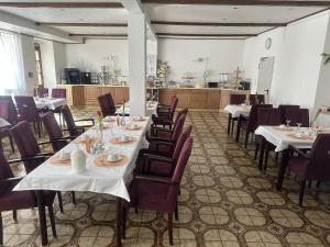 a dining room with tables and chairs and a kitchen at Hotel Eulenhof in Gransdorf +24 photos
