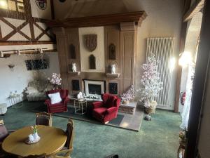 a living room with red chairs and a fireplace at Hotel Eulenhof in Gransdorf