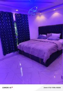 a purple bedroom with a large bed with purple lighting at Ngalle guest house in Buea