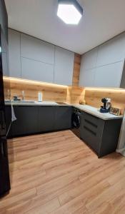 a kitchen with white cabinets and a wooden floor at By The Pool Apartments #8 in Velingrad