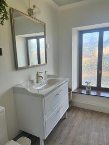 a white bathroom with a sink and a mirror at Escapade Chic in Renwez