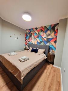a bedroom with a large bed with a colorful wall at By The Pool Apartments #8 in Velingrad