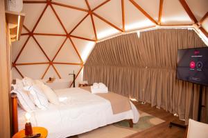a bedroom with a bed and a tv in a tent at Refúgio Kuri'y Campos do Jordão in Campos do Jordão