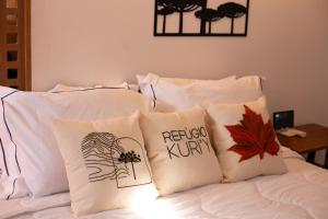 a pile of pillows on a bed with autumn leaves at Refúgio Kuri'y Campos do Jordão in Campos do Jordão