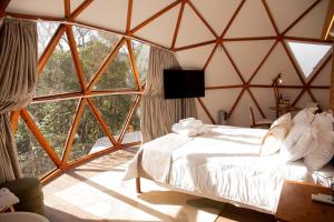 a bedroom with a bed and a large window at Refúgio Kuri'y Campos do Jordão in Campos do Jordão
